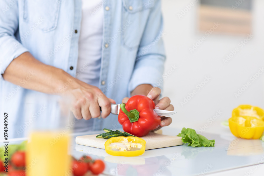 Close up of male hands chopping vegetables on a cutting board at he kitchen.