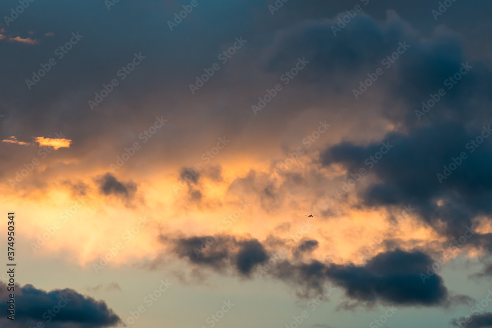 An airplane in Brasilia seen against a bright sunset and dark clouds.