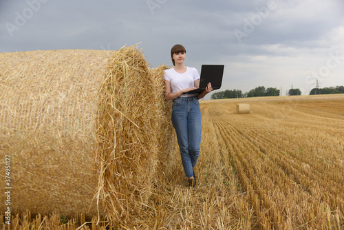 Close-up of bales of straw, next to a girl with a laptop. © BAR