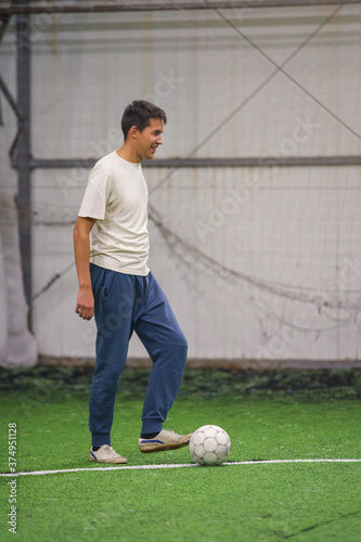 man playing football indoor on green lawn on soccer arena. Amateur sport photo