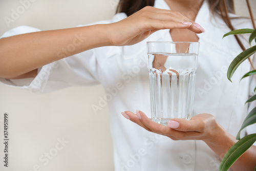 Close up photo of woman's hands in circle with glass of water in a white robe.
