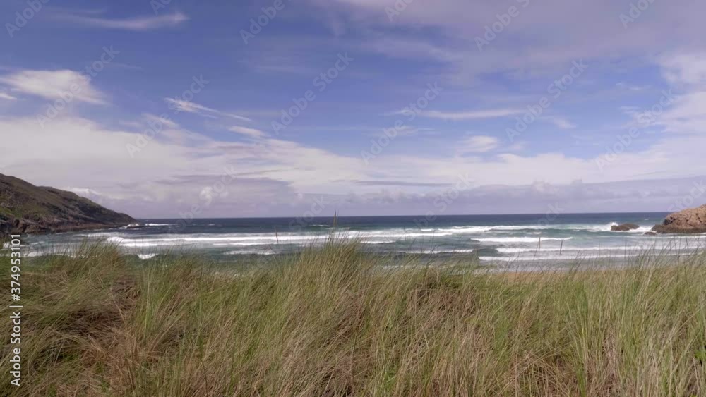 Stunning Landscape Of Ocean With Rolling Waves Under The Bright Blue Sky In Cave Beach Island, Donegal, Ireland. - push in shot Stunning Landscape Of Ocean With Rolling Waves Under The Bright Blue Sky In Cave Beach Island, Donegal, Ireland. - push in shot
