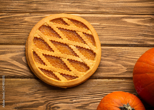 Pumpkin pie on rustic wooden background with whole pumpkins. Traditional American autumn, Thanksgiving and Halloween sweet pie, seasonal fall dessert. Close up, top view.