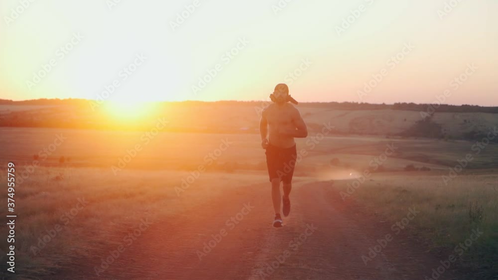 A muscular, athletic Arab man with a beard running on beautiful sunset background. Oriental Male runner run. Cardio exercise at workout outdoor. Slow motion