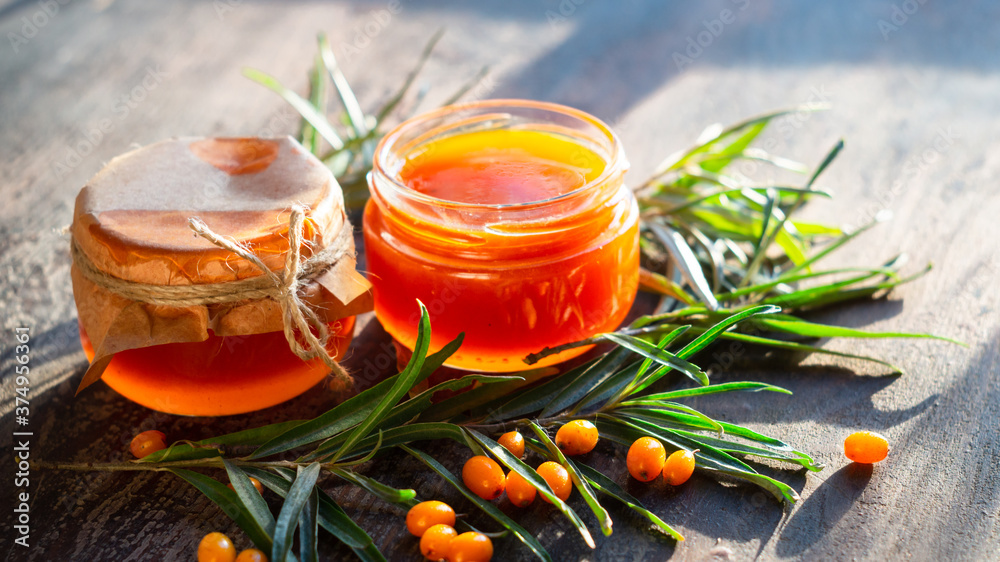 Sea buckthorn jam in glass jars, branch and berries Sea buckthorn jam in glass jars, branch and berries
