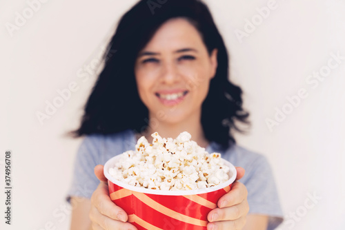 Closeup on bucket with popcorn in hand of young woman