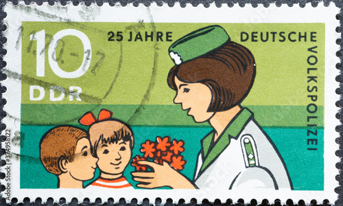GERMANY, DDR - CIRCA 1970: a postage stamp from Germany, GDR showing a policewoman with children. Text: 25 years of the People's Police
