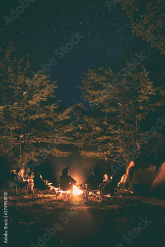 The group of young people are sitting around the bonfire and talking and singing songs