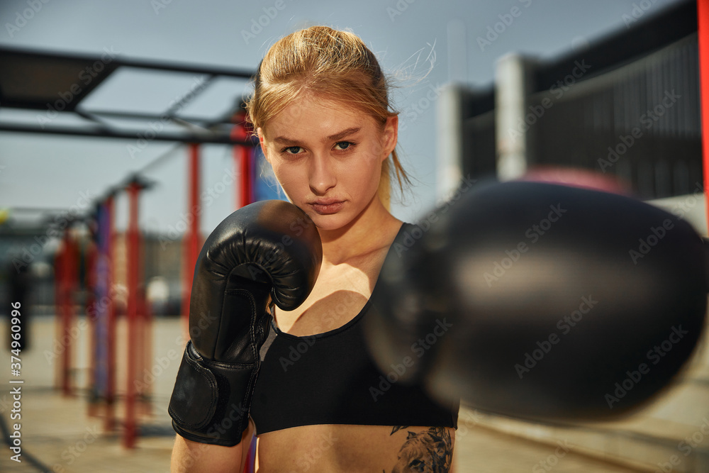 Sporty female in boxing black glove on the sports ground