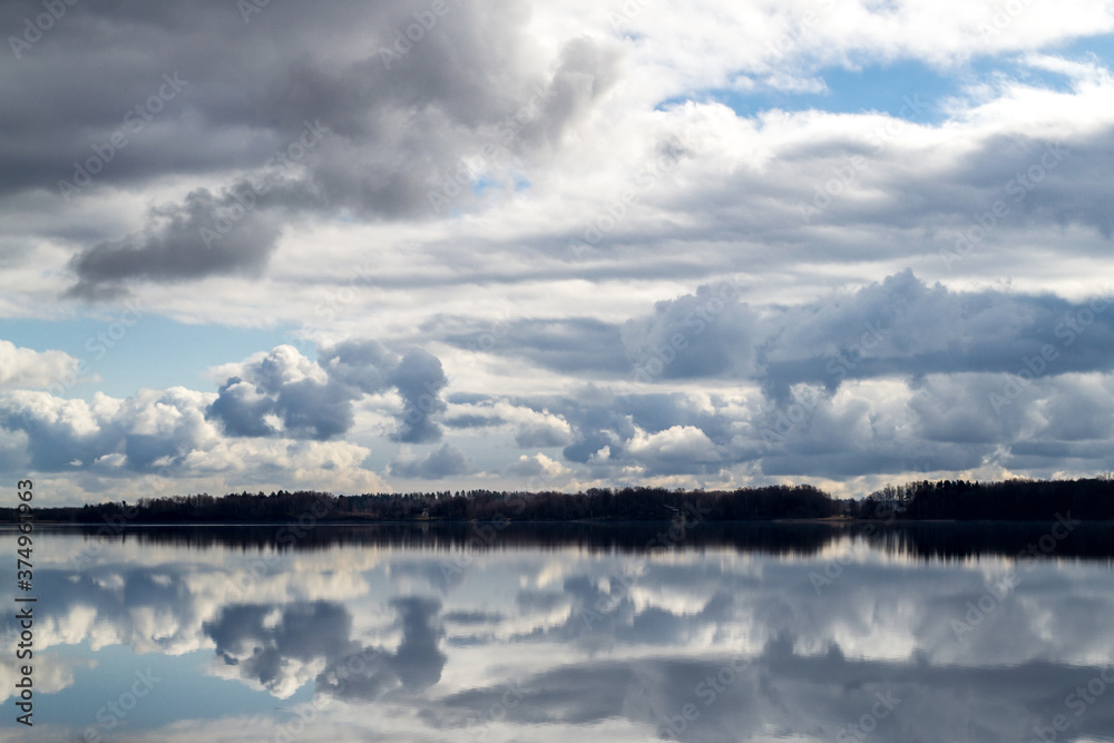 Beautiful clouds in the blue sky and reflected in the water. The Daugava river near Riga. Picturesque view. The nature of Latvia.