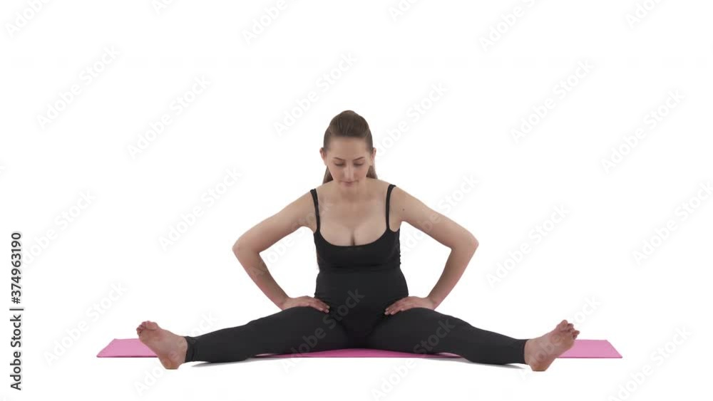 Stretching routine. Pregnant Caucasian woman sitting on mat, extends legs wide and bending forward. Isolated on white background. Stretching routine. Pregnant Caucasian woman sitting on mat, extends legs wide and bending forward. Isolated on white background.