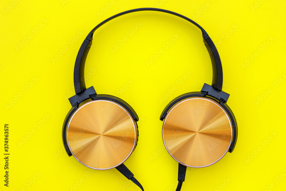 Modern orange headphone on yellow background. Music concept.