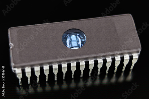 Erasable programmable read-only memory. EPROM chip on black background. Digital integrated circuit die with thin silver wires in DIP package with transparent window to erase data by ultraviolet light.