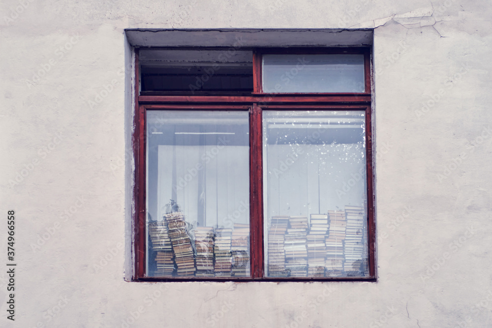 Obraz premium Window of the house with a stack of books on the windowsill library