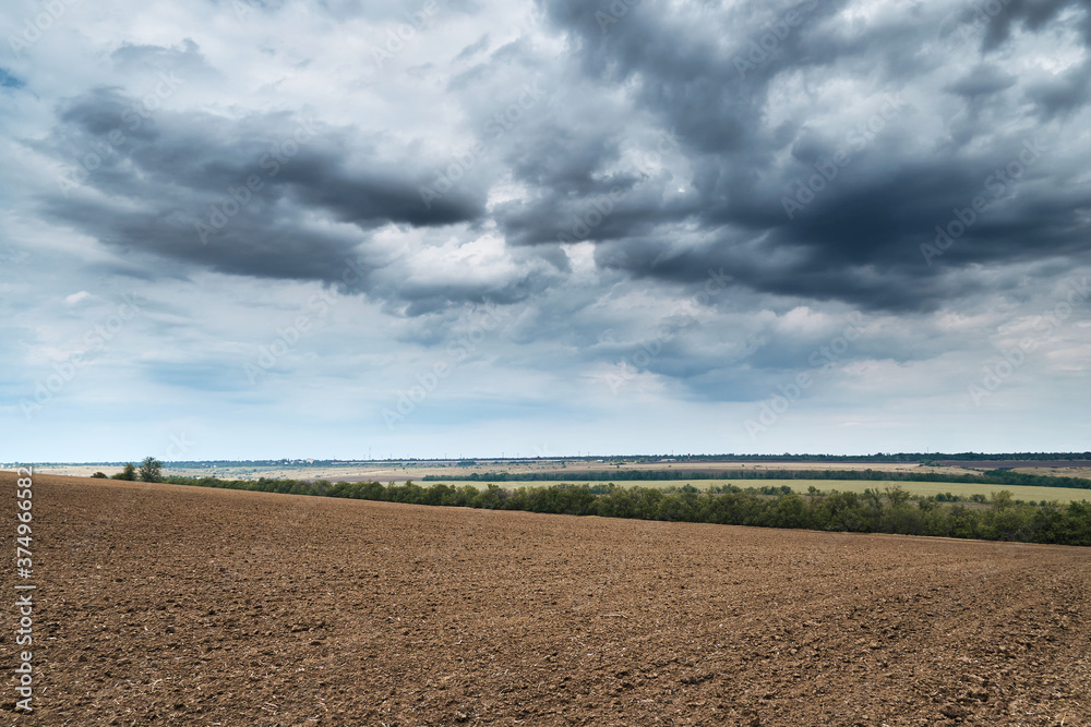 plowed field and dramatic blue sky, soil and clouds of a bright sunny day - concept of agriculture plowed field and dramatic blue sky, soil and clouds of a bright sunny day - concept of agriculture