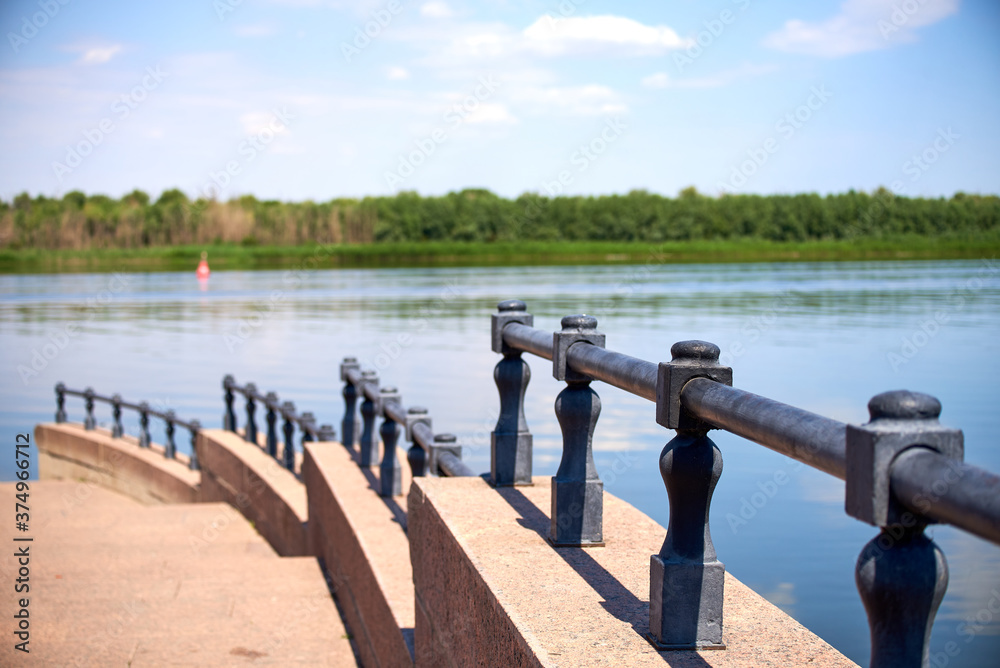 Close-up of an iron stepped fence against a blurred background of the Volga river