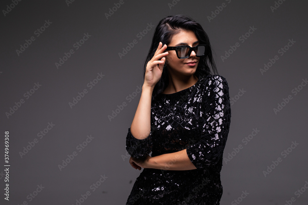 Portrait of beautiful woman in black dress and sunglasses on gray background Portrait of beautiful woman in black dress and sunglasses on gray background