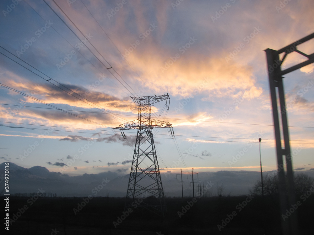 power lines against a beautiful sky and clouds and mountains. Sunset.