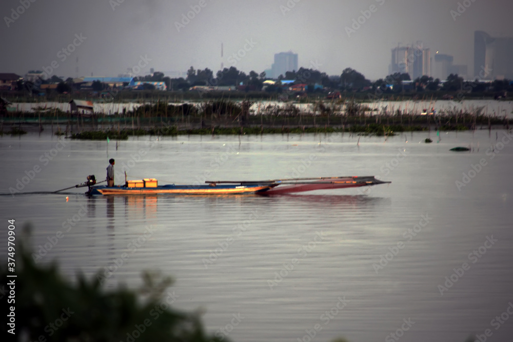 Obraz premium Fisherman on a motor boat on a lake in the evening