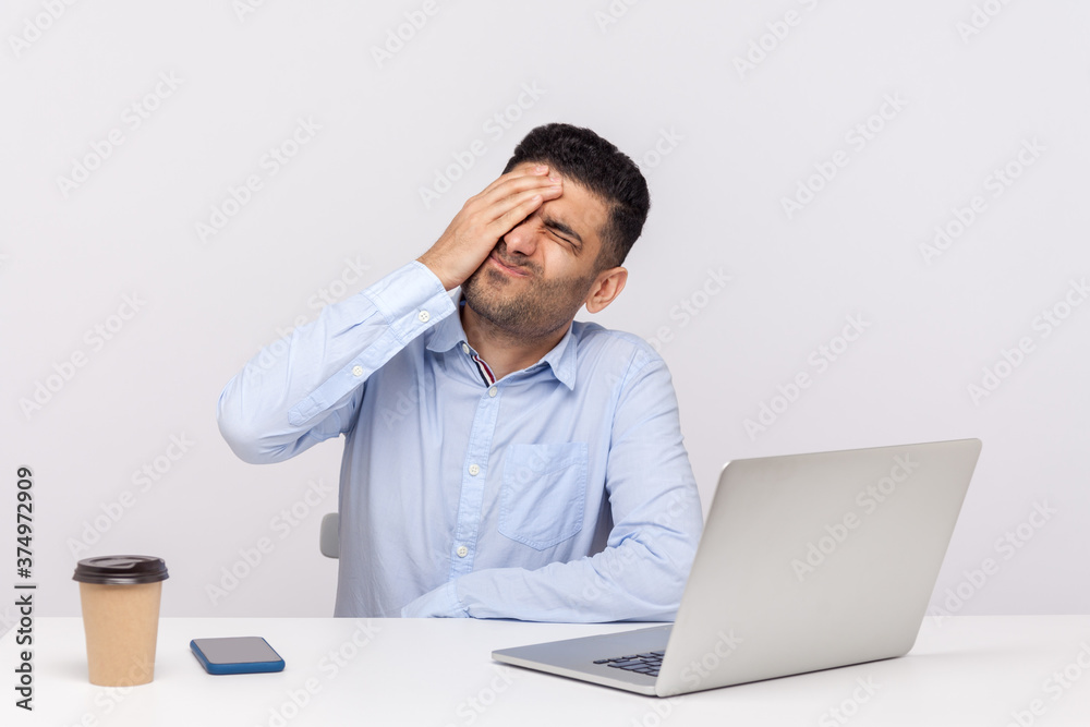 Facepalm. Depressed businessman sitting office workplace, keeping hand on forehead, blaming himself for mistake, forgotten business meeting, expressing sorrow. studio shot isolated on white background Facepalm. Depressed businessman sitting office workplace, keeping hand on forehead, blaming himself for mistake, forgotten business meeting, expressing sorrow. studio shot isolated on white background