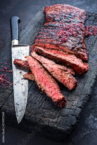 Barbecue wagyu bavette beef steak with red wine salt offered as close-up on charred wooden black board photo