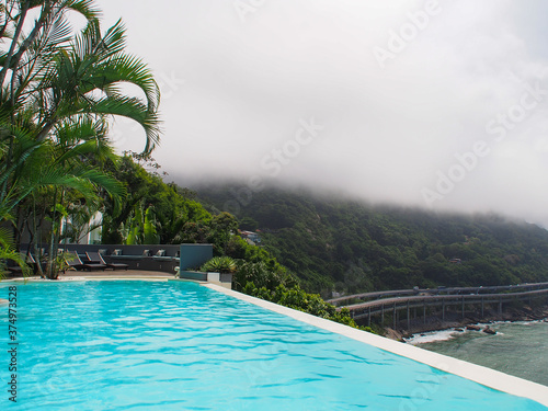 Rio de Janeiro view from the pool  green mountains  ocean  clouds and sun.