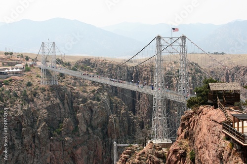 People Walking Over Royal Gorge Bridge With American Flag Flying In Wind
