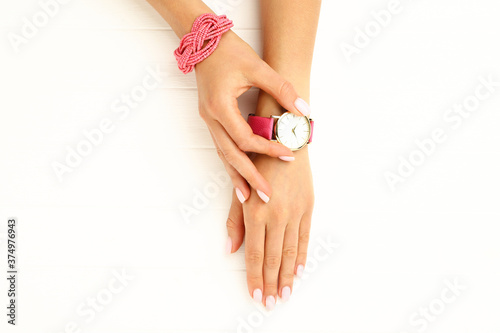 Female hand with bracelet and wrist watch on white wooden background