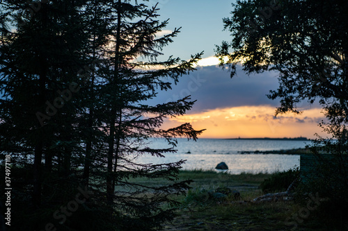 landscape with sea and coastline against the background of blue clouds and the setting sun on the northern island