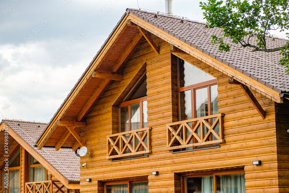 Modern wooden house with big windows and balcony. Concept of building of family houses, pensions or cottages in the countryside. Building of houses under the key Modern wooden house with big windows and balcony. Concept of building of family houses, pensions or cottages in the countryside. Building of houses under the key