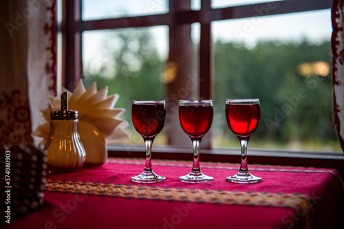 eyelets with red liqueur on the table with a red tablecloth against the background of the window