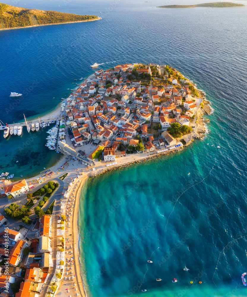 Primosten town, Croatia. View of the city from the air. Seascape with beach and old town. View from drone on the peninsula with houses. Landscape during sunset. Travel image - obrazy, fototapety, plakaty 