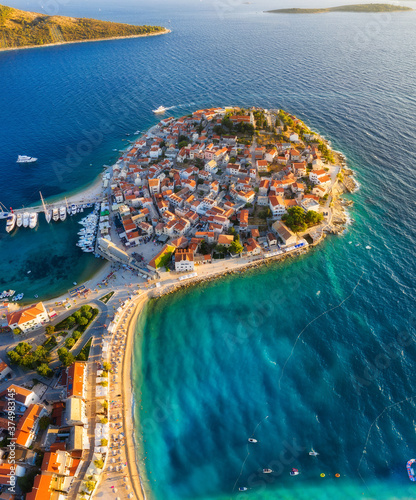 Fototapeta Naklejka Na Ścianę i Meble -  Primosten town, Croatia. View of the city from the air. Seascape with beach and old town. View from drone on the peninsula with houses. Landscape during sunset. Travel image