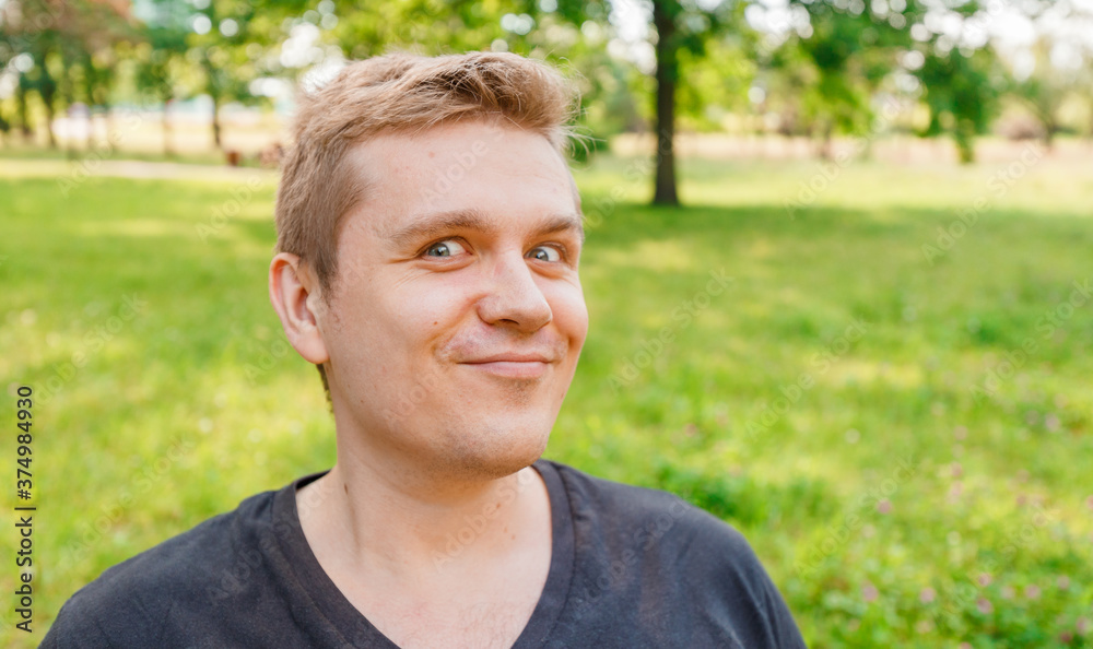 Portrait of a young man on nature background. Emotion facial expression.