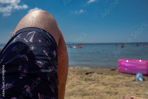 Man sunbathing on the beach and watching people at sea, mini pool on the sand, turtle, crab, sea horse, dolphin and sailbot image on sea short