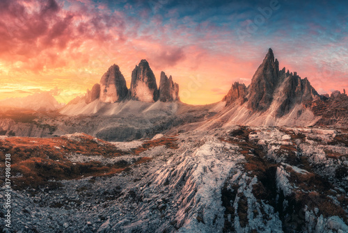 Mountains and beautiful sky with colorful clouds at sunset. Autumn landscape with mountains  stones  grass  sky with red and orange clouds. High rocks in fall. Tre Cime in Dolomites  Italy. Travel