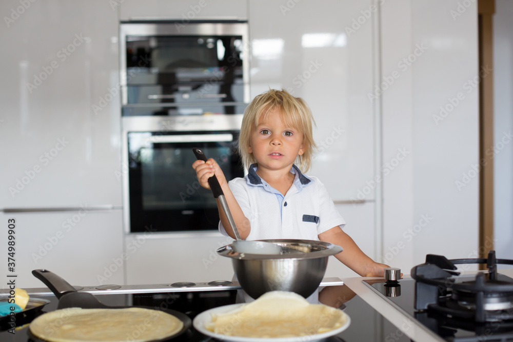 Cute toddler child, blond boy, making pancake in kitchen Cute toddler child, blond boy, making pancake in kitchen