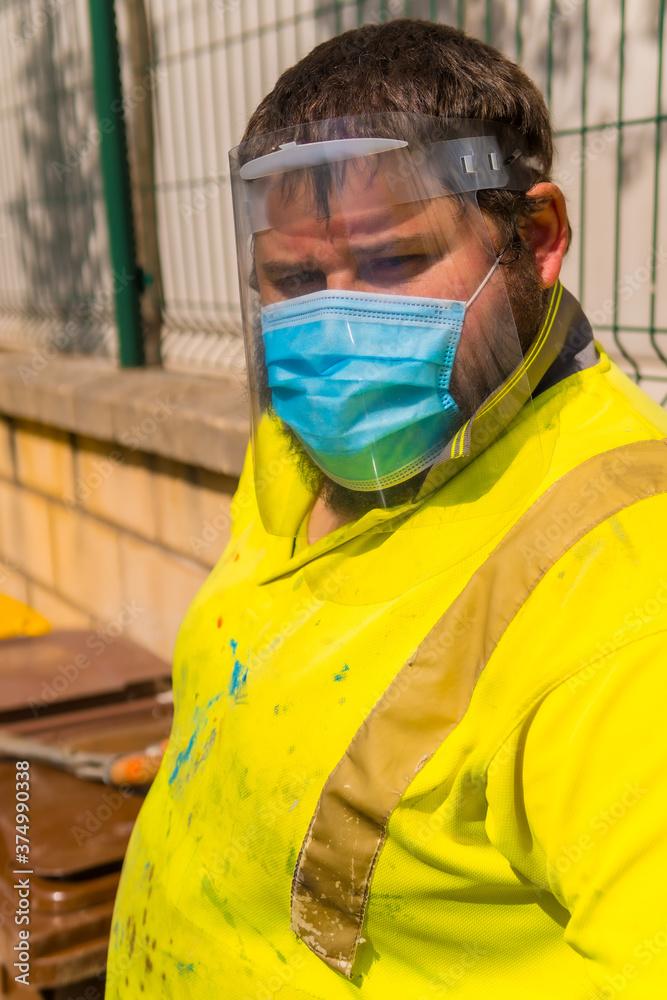 Worker in a recycling factory or clean point and garbage with a face mask and plastic protective screen, new normal, coronavirus pandemic, covid-19. Plant worker portrait Worker in a recycling factory or clean point and garbage with a face mask and plastic protective screen, new normal, coronavirus pandemic, covid-19. Plant worker portrait