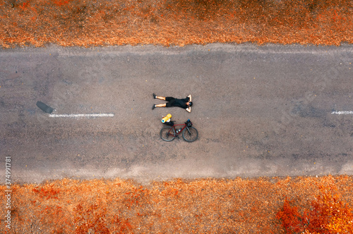 Obraz na plátně Top view of a cyclist with a road bike lying on the asphalt