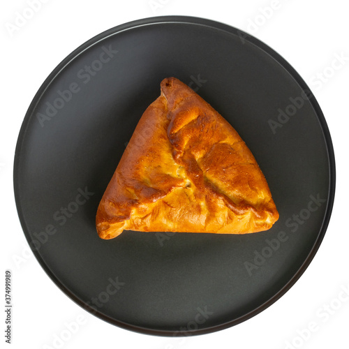 Isolate of a round black dish with a triangular pie, samsa or echpochmak. View from above