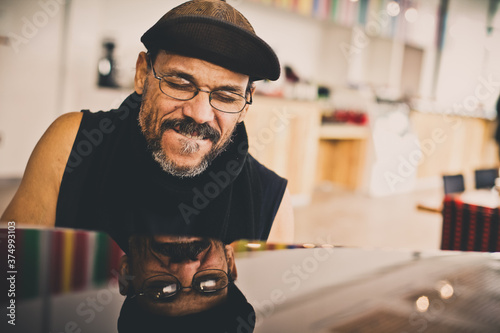 african american man with joyous face playing piano with his reflection in piano top