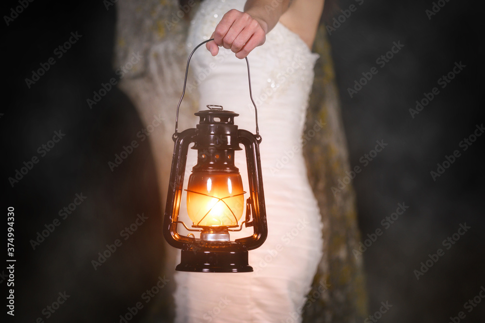 Unrecognizable Woman with Vintage Lantern Outside at Night. Young woman in white long dress walking in night wood. High quality photo