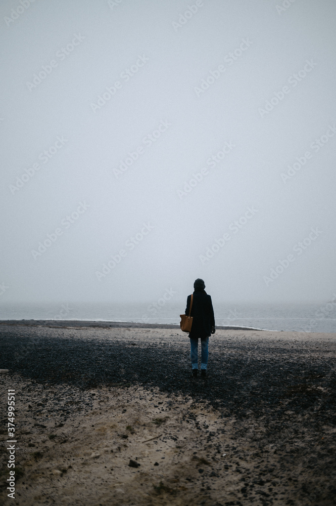 the girl walks along the foggy seashore