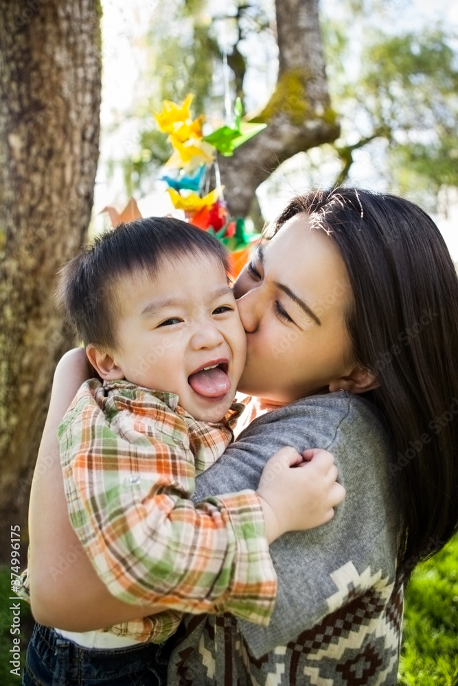 Asian mother kissing her happy and cute son Asian mother kissing her happy and cute son