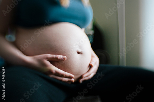 Sitting Mother Holds Hands on Pregnant Belly