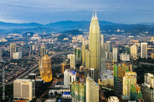 Asia, Malaysia, Selangor State, Kuala Lumpur, elevated view of iconic 88 storey steel-clad Petronas Towers and KL city centre skyline - illuminated at dusk photo