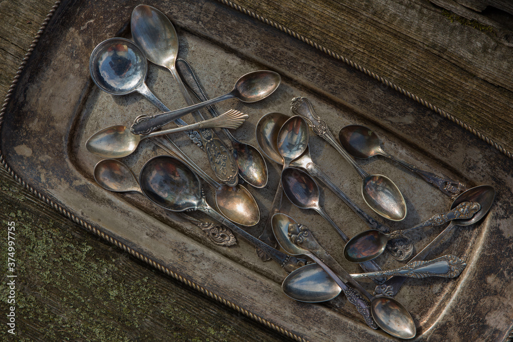 Antique spoons and utensils in a silver plate covered with patina on an old wooden background Antique spoons and utensils in a silver plate covered with patina on an old wooden background