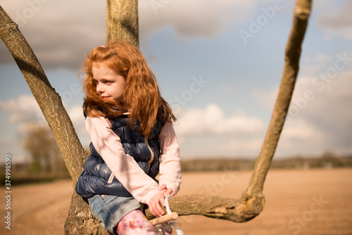 Girl climbing tree in countryside photo