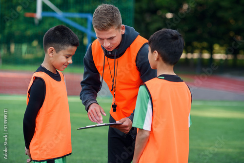 Football coach instruct teen football players. Young professional coach explains for kids the strategy of the game. photo