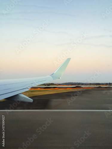 View of an airplane wing and rain on the window and tarmac